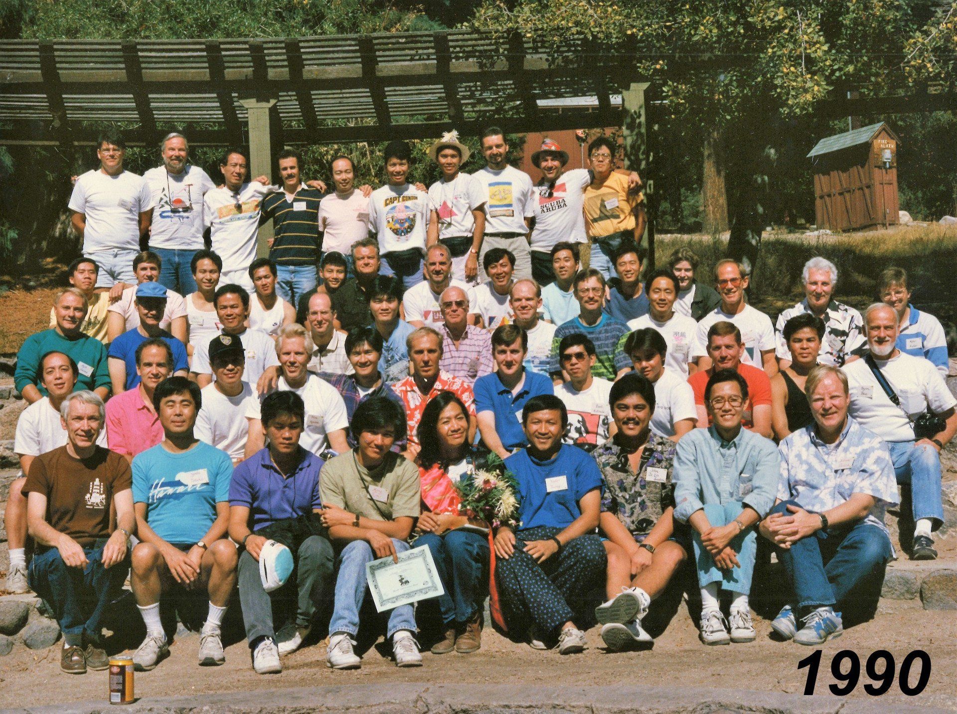 A large group of A/PLG members posing together outdoors in 1990