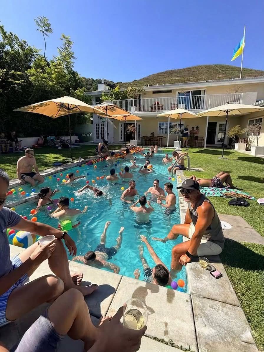 Members swimming and relaxing around a backyard pool in the Hollywood Hills at the 2026 Pride Pool Party